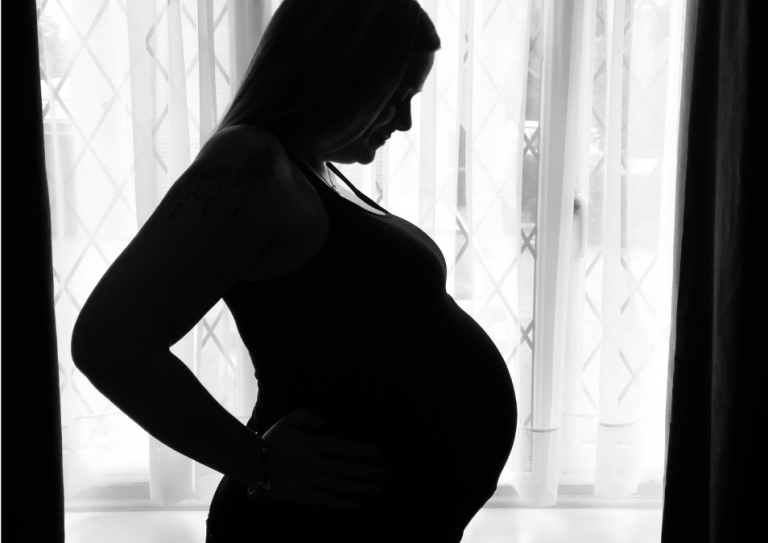 A black and white side silhouette of Lisa against a window. She is heavily pregnant