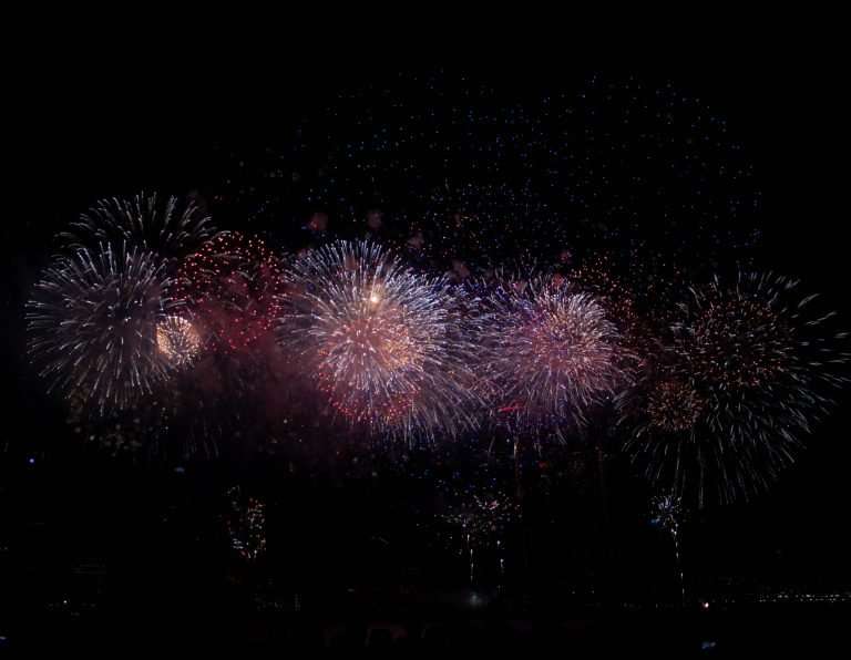 Far away shot of fireworks exploding against the black night sky