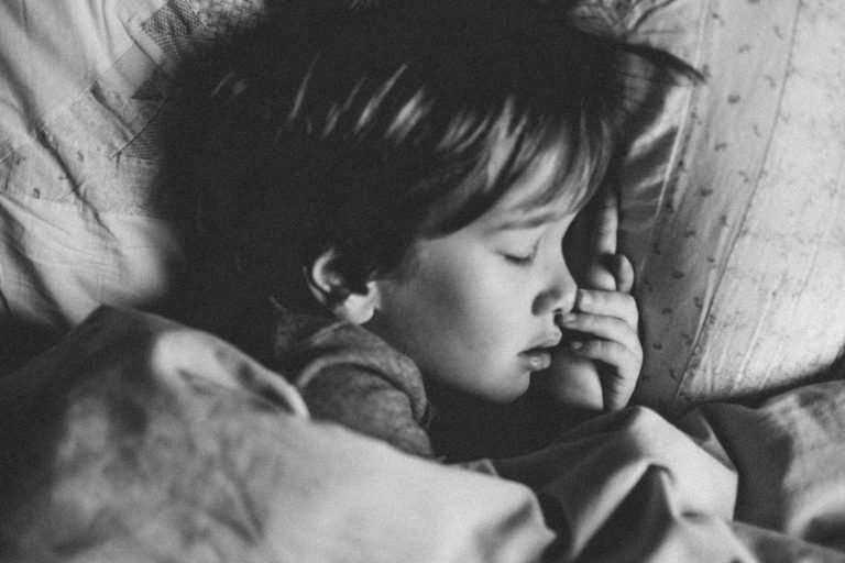A black and white picture of a child sleeping in their bed