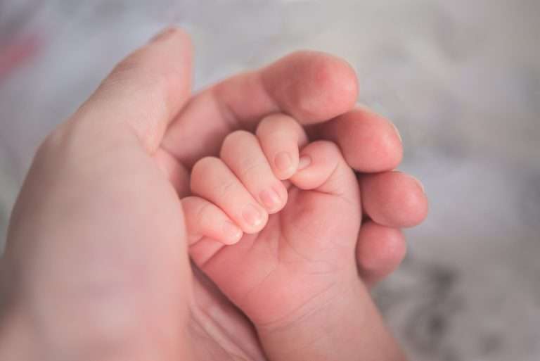 Close up of a hand with a baby's hand nestled inside
