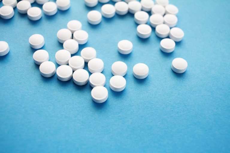 Lots of Clomid tablets spilt on a blue background