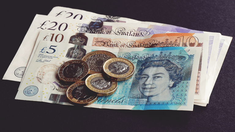 On a black table is UK money. There is; 2x £20 notes 1x £10 note 1x £5 note 1x £2 coin and 4x £1 coins
