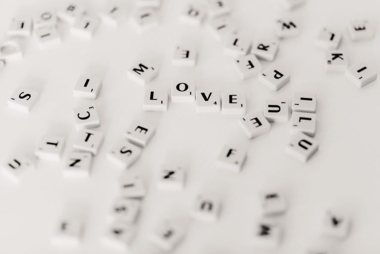 Lots of different scrabble pieces scattered around on a white table